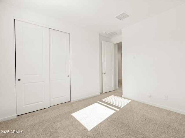 unfurnished bedroom featuring light colored carpet and a closet