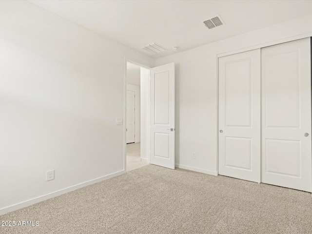 unfurnished bedroom featuring light colored carpet and a closet