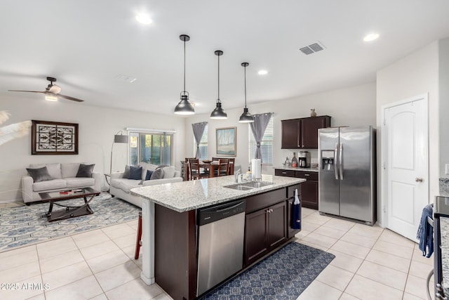 kitchen featuring pendant lighting, stainless steel appliances, a kitchen island with sink, ceiling fan, and sink