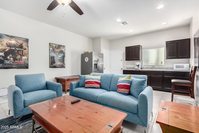 living room with ceiling fan, light tile patterned flooring, and sink