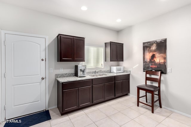 kitchen with sink, light tile patterned floors, and dark brown cabinets