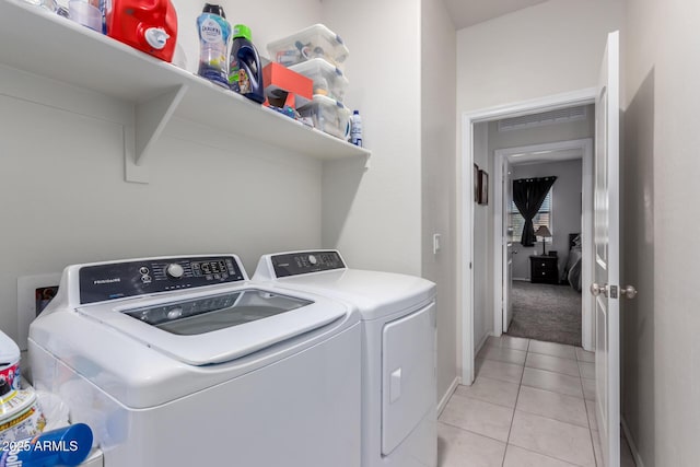 laundry room with washing machine and clothes dryer and light tile patterned floors