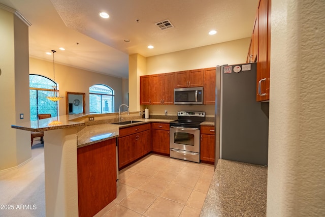 kitchen featuring visible vents, appliances with stainless steel finishes, brown cabinets, a peninsula, and a sink