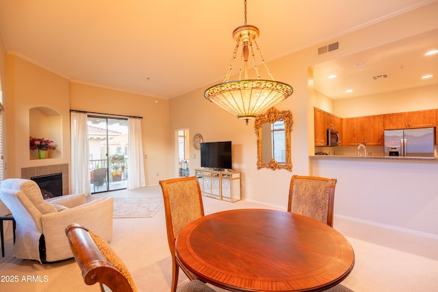 dining room with recessed lighting, visible vents, a tiled fireplace, ornamental molding, and light carpet