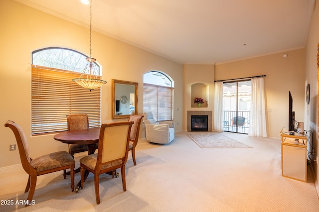 dining room with carpet floors, baseboards, ornamental molding, and a tiled fireplace