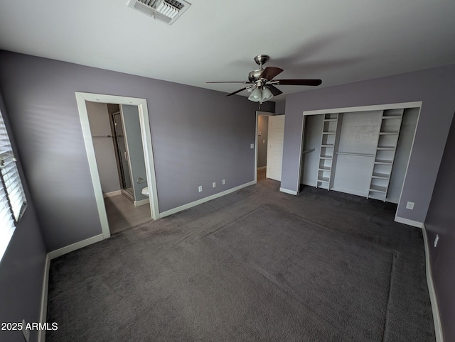 unfurnished bedroom with baseboards, visible vents, dark colored carpet, and a closet