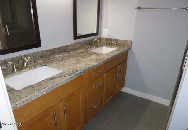 bathroom with a sink, baseboards, and double vanity