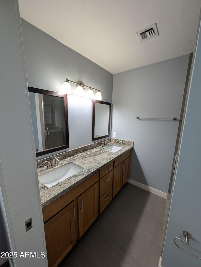 bathroom featuring visible vents, a sink, a shower with door, and double vanity