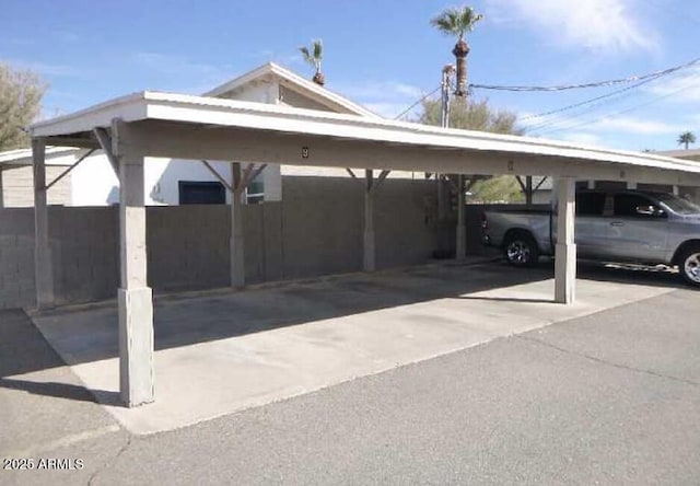 covered parking lot featuring fence