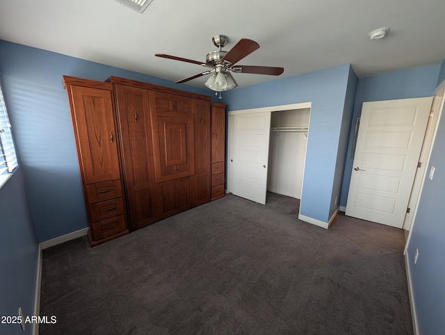 unfurnished bedroom featuring a ceiling fan, baseboards, dark colored carpet, and a closet