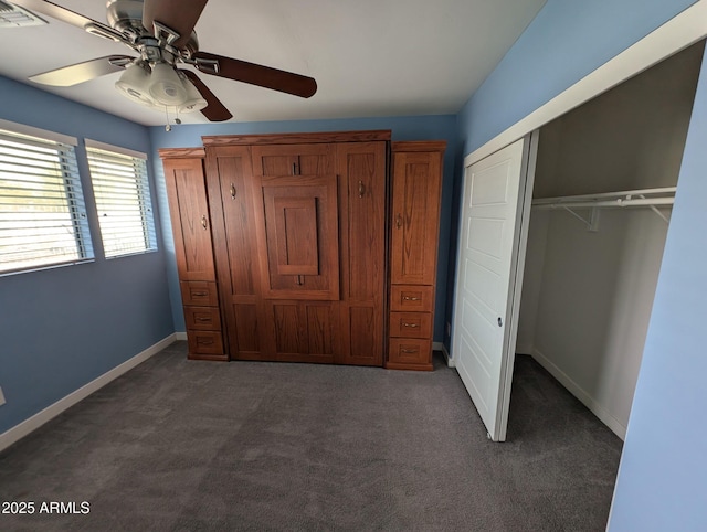 unfurnished bedroom featuring baseboards, visible vents, ceiling fan, dark carpet, and a closet