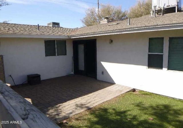 property entrance with roof with shingles and stucco siding