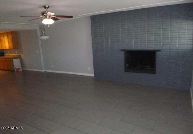 unfurnished living room with a fireplace, baseboards, and a ceiling fan