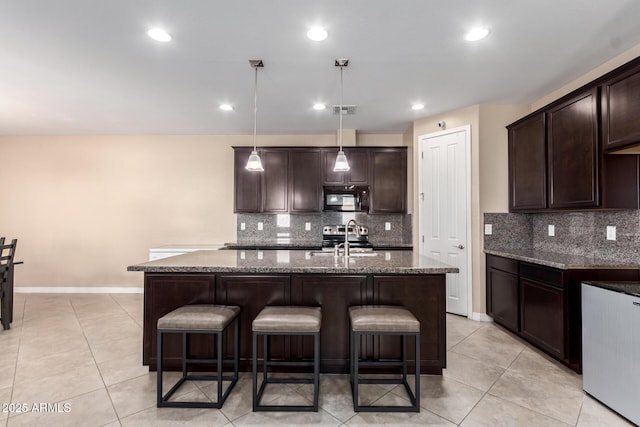 kitchen featuring visible vents, dark brown cabinets, a kitchen bar, black microwave, and a sink