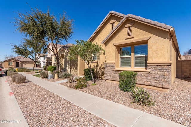 view of front of property with stone siding, a tiled roof, and stucco siding