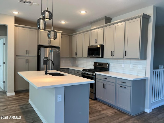 kitchen with hanging light fixtures, sink, dark hardwood / wood-style flooring, an island with sink, and stainless steel appliances