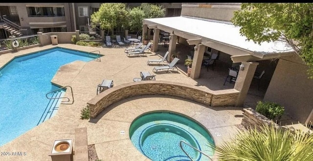 view of swimming pool featuring a hot tub and a patio