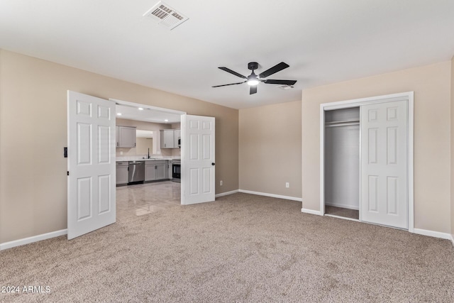 unfurnished living room with light colored carpet, ceiling fan, and sink