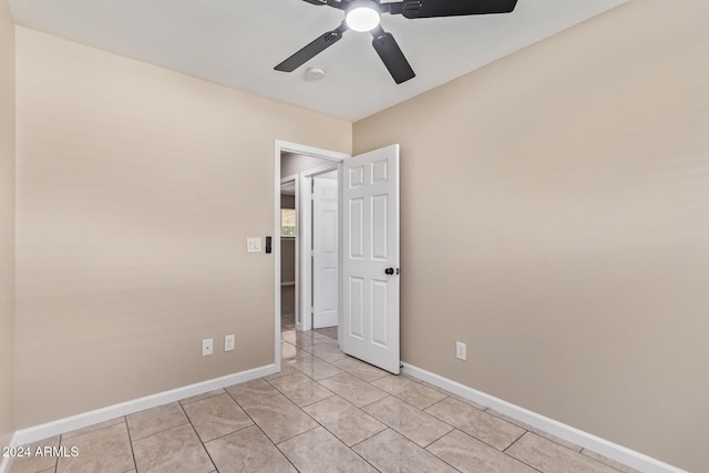 empty room with ceiling fan and light tile patterned floors