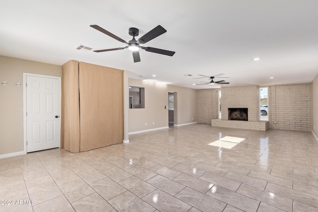 unfurnished living room featuring ceiling fan, light tile patterned flooring, brick wall, and a brick fireplace