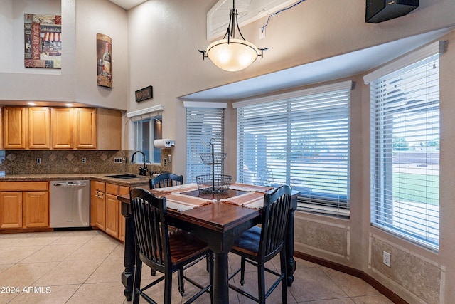 tiled dining area with a high ceiling, plenty of natural light, and sink