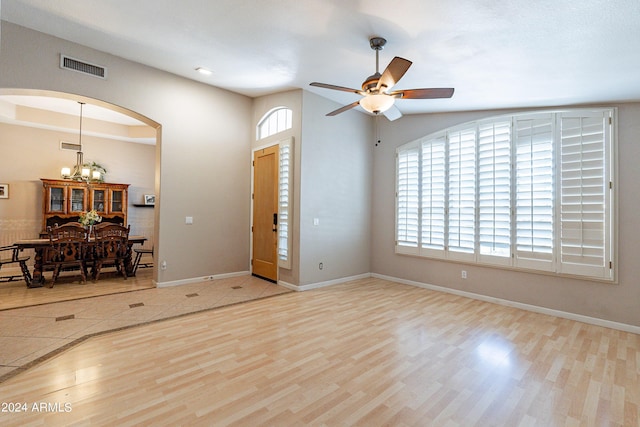 entrance foyer with ceiling fan with notable chandelier and light wood-type flooring