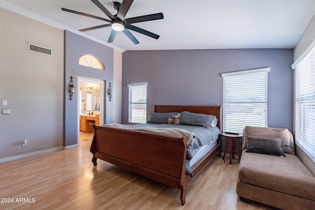 bedroom featuring ceiling fan, light wood-type flooring, connected bathroom, and vaulted ceiling