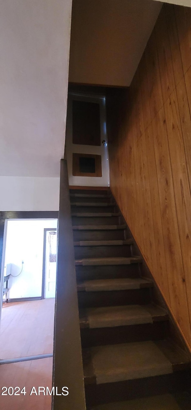 stairway featuring wood walls