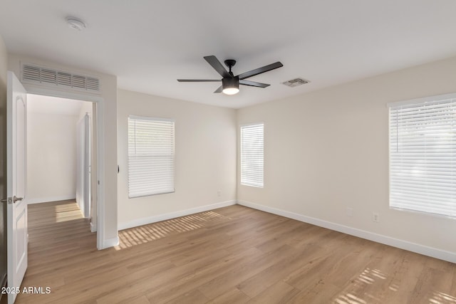 empty room with visible vents, baseboards, light wood-style flooring, and a ceiling fan