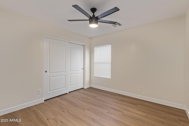 unfurnished bedroom featuring a ceiling fan, baseboards, visible vents, a closet, and light wood-type flooring