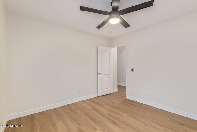 spare room with light wood finished floors, ceiling fan, and baseboards