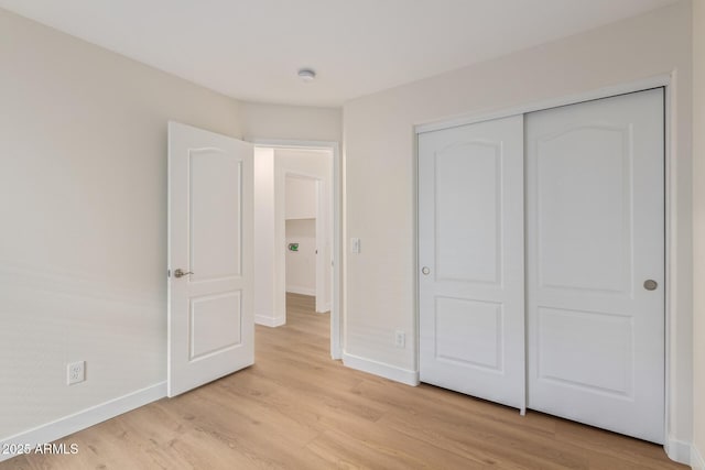 unfurnished bedroom featuring a closet, baseboards, and light wood-style floors