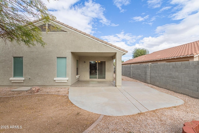 back of property featuring a tiled roof, a patio area, a fenced backyard, and stucco siding