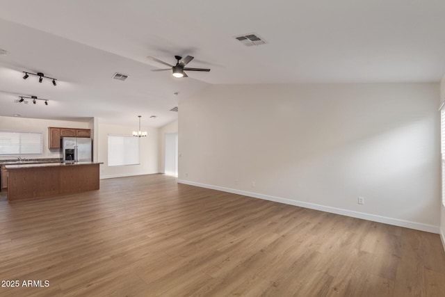 unfurnished living room featuring visible vents, wood finished floors, and ceiling fan with notable chandelier