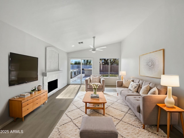 living room featuring light hardwood / wood-style floors, lofted ceiling, ceiling fan, and a fireplace