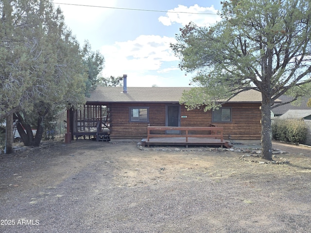 log cabin featuring a deck, log exterior, and roof with shingles