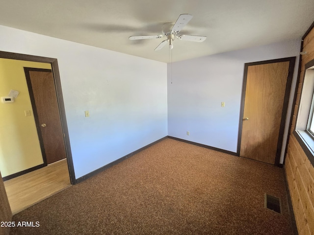 carpeted spare room featuring visible vents, baseboards, and a ceiling fan