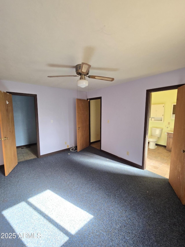 unfurnished bedroom with a ceiling fan, ensuite bath, baseboards, and carpet flooring