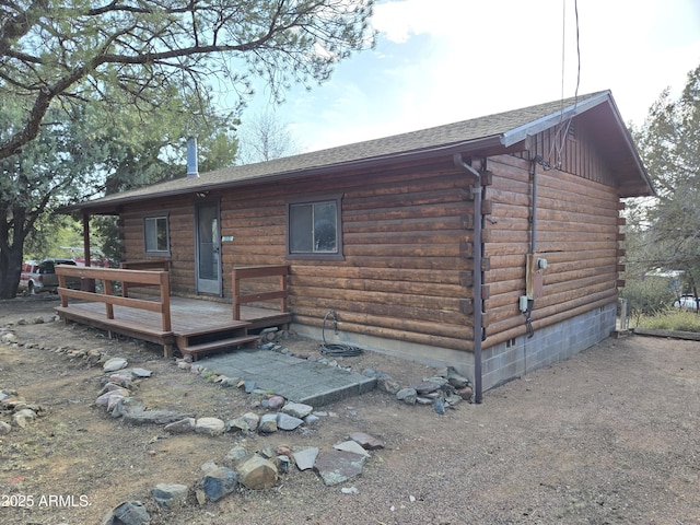 log-style house with roof with shingles, log exterior, and a wooden deck