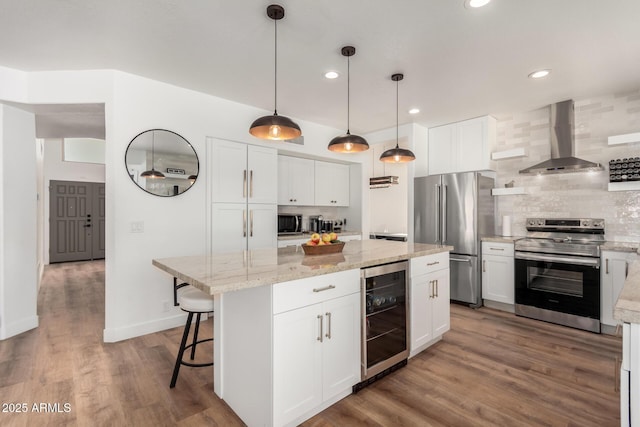 kitchen featuring white cabinetry, a kitchen island, stainless steel appliances, beverage cooler, and wall chimney range hood