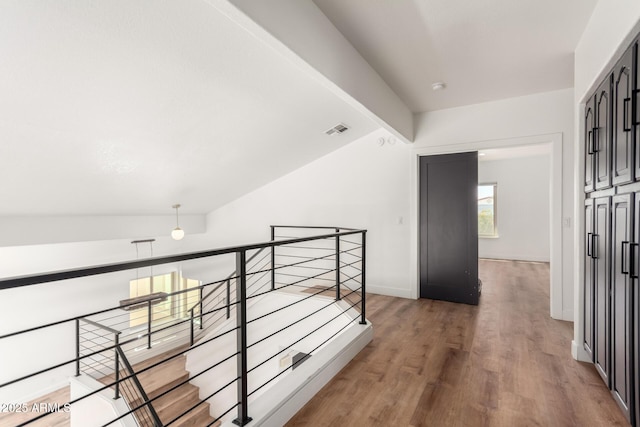 hall with hardwood / wood-style floors and vaulted ceiling with beams