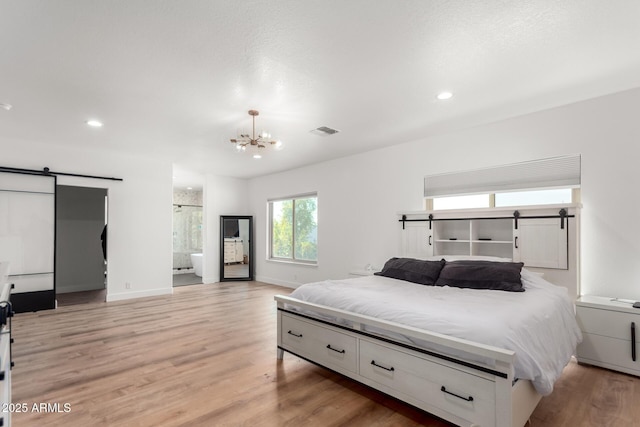 bedroom featuring a barn door, a chandelier, and light wood-type flooring