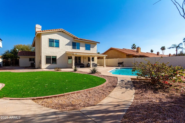 back of property with a fenced in pool, a yard, and a patio area