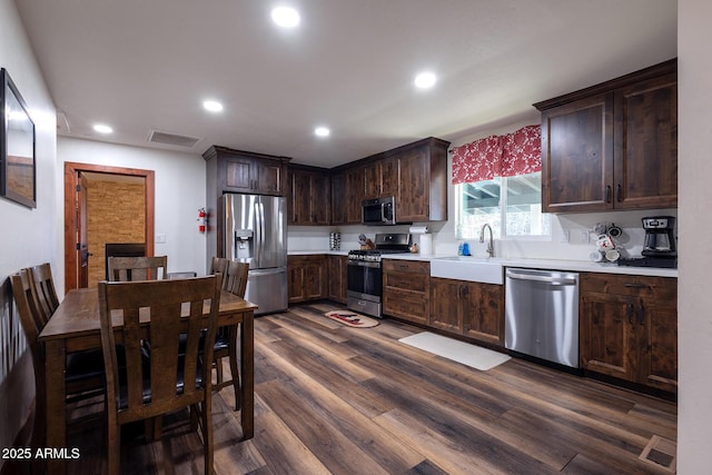 kitchen with dark wood finished floors, appliances with stainless steel finishes, light countertops, dark brown cabinets, and a sink