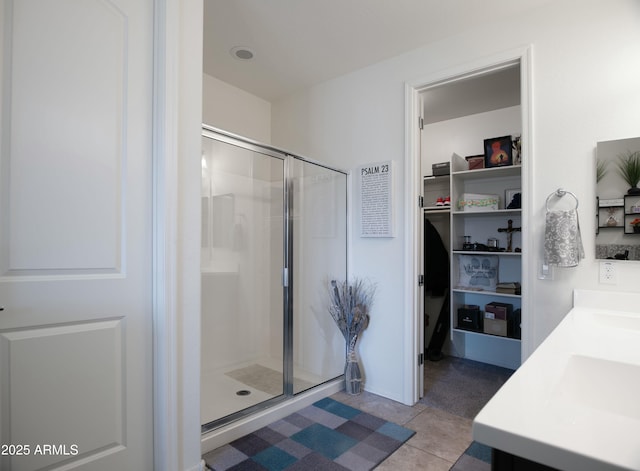 full bathroom with double vanity, a stall shower, and tile patterned flooring