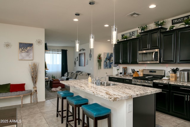 kitchen with visible vents, a sink, open floor plan, stainless steel appliances, and dark cabinets