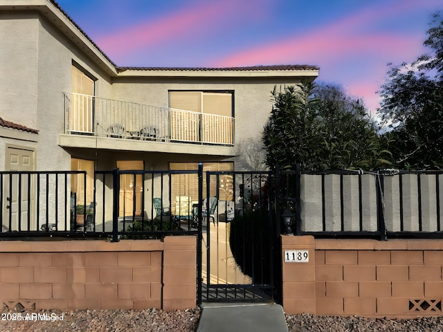 view of front of property featuring a tiled roof, fence, a gate, and stucco siding