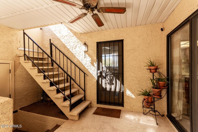 entrance foyer with a textured wall, a ceiling fan, and stairs