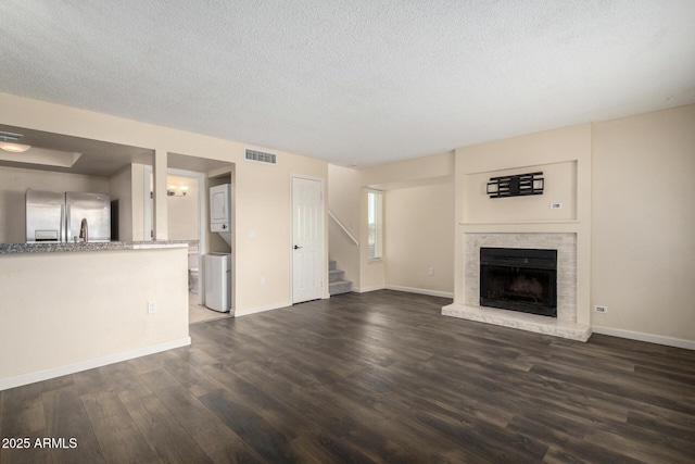1645 W Baseline Rd Unit 2098, Mesa, AZ 85202 - unfurnished living room with stacked washing machine and dryer, stairs, dark wood finished floors, a textured ceiling, and baseboards
