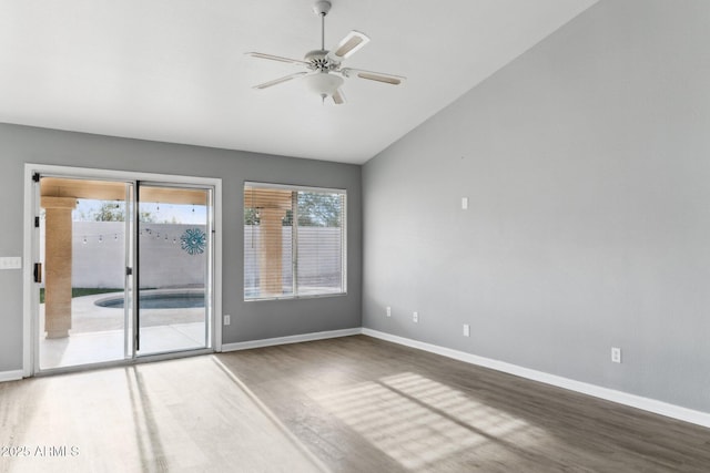 empty room featuring lofted ceiling, ceiling fan, hardwood / wood-style flooring, and a healthy amount of sunlight